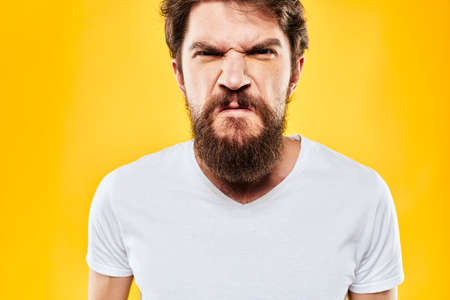 emotional bearded man in t-shirt cropped view yellow background studioの写真素材