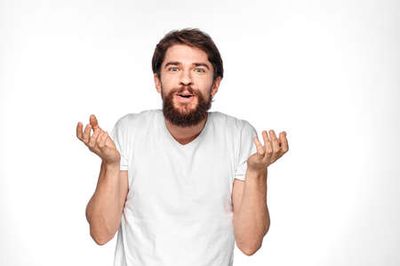 Bearded man in white t-shirt gesture with hands emotions light backgroundの写真素材