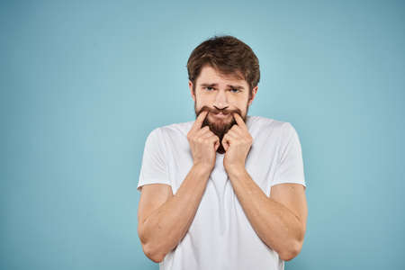 Man in white t-shirt lifestyle studio emotions facial expression blue isolated backgroundの写真素材