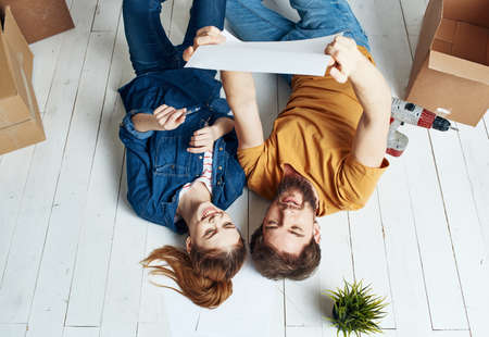 A woman-man with a flower in a pot lie on the floor In a bright room near the sofaの写真素材