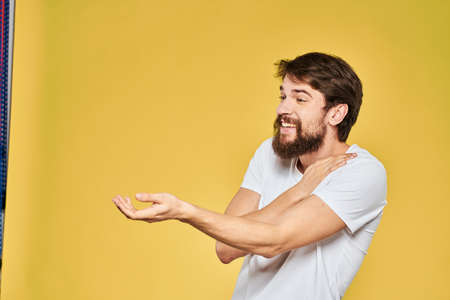 Man gesturing with hands emotions lifestyle white t-shirt yellow isolated backgroundの写真素材