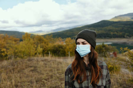 Female portrait medical mask autumn dry grass mountainsの写真素材