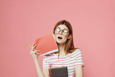 beautiful female student holding books education institute gesturing with hands pink background Copy...