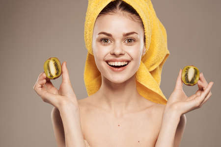 cheerful woman with a towel on her head and hands skin care naked shoulders beige background