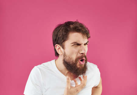 Angry man yells on pink background stress irritability modelの写真素材