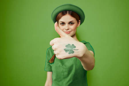 Happy woman with shamrock on St. Patricks Day in green clothes and a hat on her head gesturing with...
