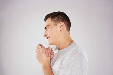 Man in a white t-shirt emotions gestures with hands close-up cropped view light backgroundの写真素材