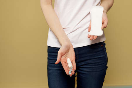 Girl with a tampon and a pad in her hand on a beige backgroundの写真素材