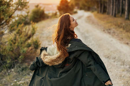 A woman with a warm jacket in her hands resting the road in natureの写真素材