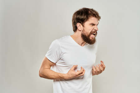 bearded man gesturing with his hands in a white t-shirt aggression light backgroundの写真素材