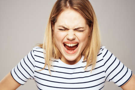 Emotional blonde woman in striped t-shirt lifestyle facial expression close-upの写真素材