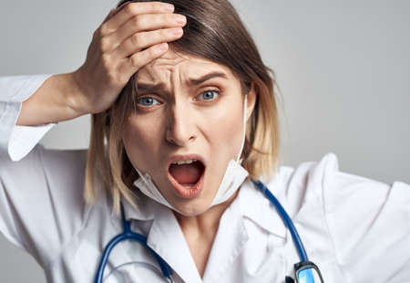 woman doctor in medical mask holding hands near face blue stethoscope cropped view