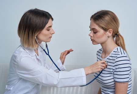 Woman doctor with stethoscope and patient at the receptionの写真素材