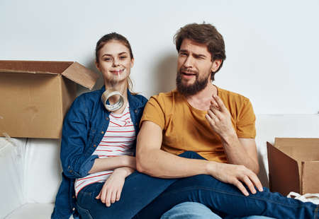 man and woman sitting on a white sofa in a room with boxes of things tools movingの写真素材