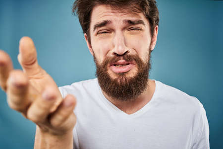 Man in white t-shirt lifestyle studio emotions facial expression blue isolated backgroundの写真素材