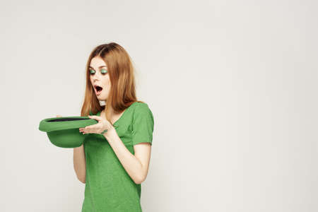 girl in green clothes with hat on light background St. Patricks day cropped view