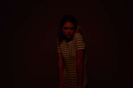 A woman in a striped T-shirt holds her hands in front of her emotions displeasure light background