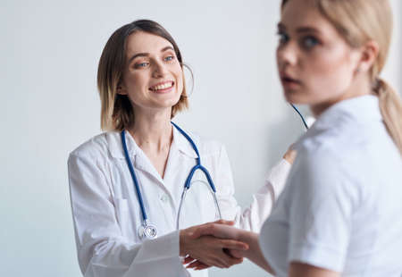 Woman doctor with glasses in hands on a light background patient communicationの写真素材
