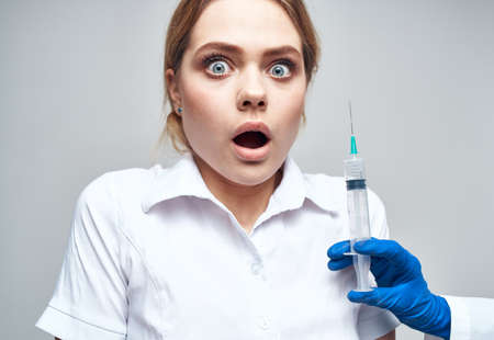 Frightened patient And syringe in hand blue gloves medicineの写真素材
