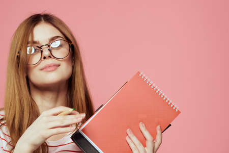 Young female student with books on pink background glasses on face education institute cropped viewの写真素材