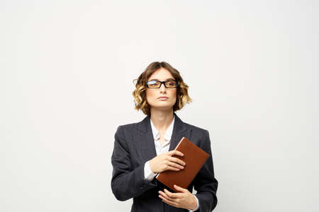 Business woman with notepad and glasses work light background cropped view of suit model.の写真素材