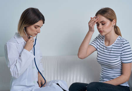 Woman doctor with stethoscope and patient at the reception