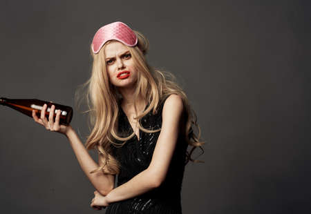 Indignant woman with a bottle of beer and a pink mask on the head of a blonde modelの写真素材
