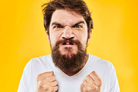 emotional bearded man gesturing with hands aggression discontent close-up yellow backgroundの写真素材