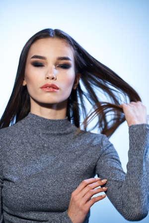 Pretty woman in gray sweater bright makeup long hair charm cropped viewの写真素材