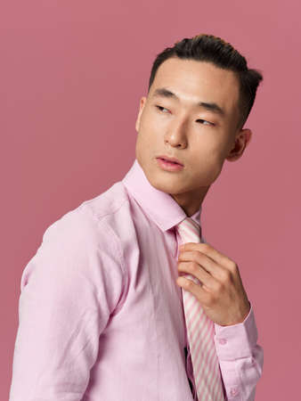 man asian appearance pink shirt straightens tie confident lifestyle