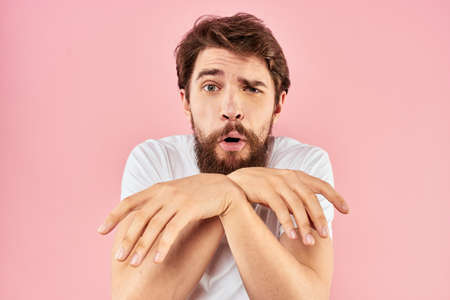 Bearded man in white t-shirt gesturing with hands facial expression close up pink backgroundの写真素材