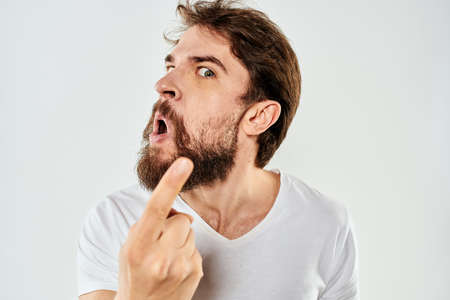 Emotional bearded man in a white t-shirt gestures with his hands light backgroundの写真素材