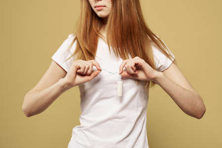 Girl with a tampon in her hand the size of the appearance of the critical days of menstruationの写真素材