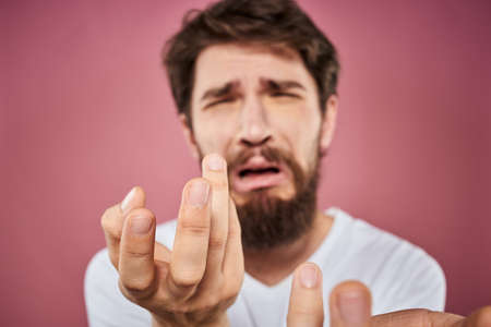 bearded man in white t-shirt emotions displeased facial expression studio pink background
