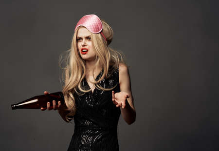 Indignant woman with a bottle of beer and a pink mask on the head of a blonde model