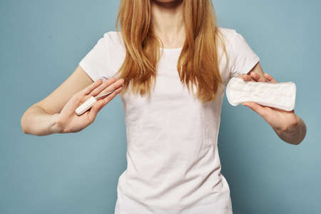Woman with tampon and pad in hand hygiene and cleanliness blue background white t-shirt cropped viewの写真素材