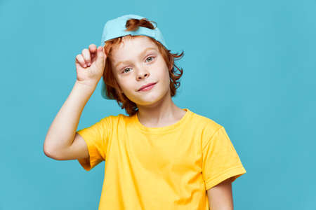 Cheerful redhead boy in blue cap yellow T-shirt fashionable clothes isolated heの写真素材