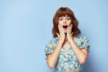 Woman in flower dress Emotions open mouth hands on face fashionable hairstyleの写真素材