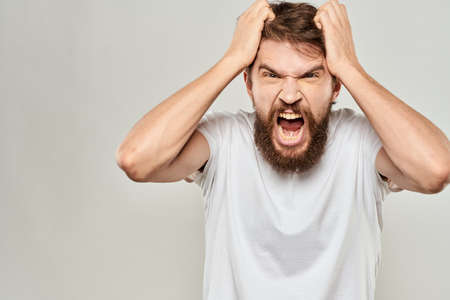 bearded man gesturing with his hands in a white t-shirt aggression light backgroundの写真素材