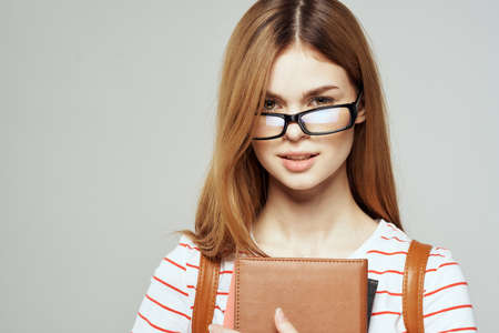 Female student with notepad and glasses on a light background cropped view of a striped T-shirtの写真素材