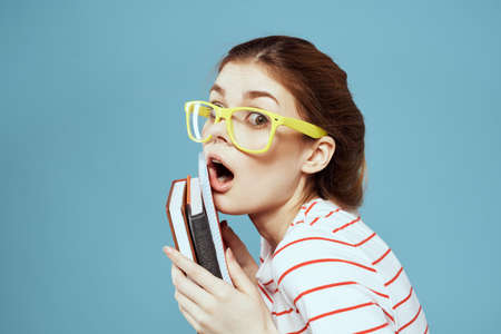 Beautiful female student with notepads and in yellow glasses on a blue background education science instituteの写真素材