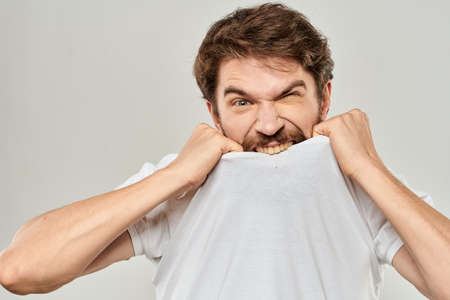 man in white t-shirt emotions expressions gesture with hands cropped view light background