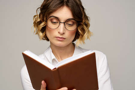 Business woman with notepad and glasses on a light background hairstyle success emotions