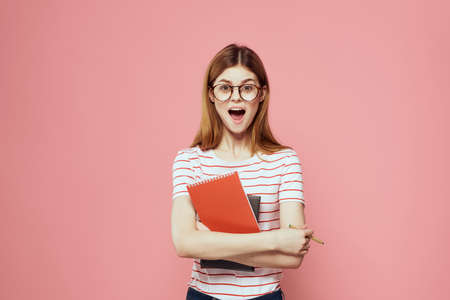 beautiful female student holding books education institute gesturing with hands pink background Copy...