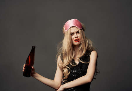 Beautiful blonde with a bottle of beer in her hand and a pink mask on her head
