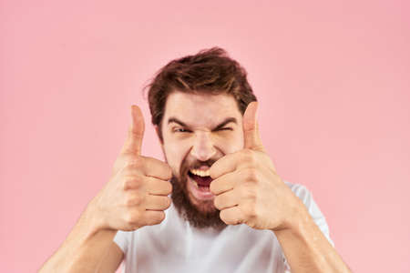 Bearded man in white t-shirt gesturing with hands facial expression close up pink backgroundの写真素材