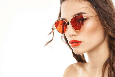 Portrait of brunette woman in sunglasses naked shoulders light background