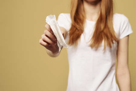 Girl with pad on beige background menstruation critical days cropped view of white t-shirtの写真素材