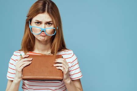 girl in fashionable glasses with notebooks in hands on a blue background cropped view Copy Space