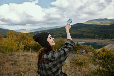 Cheerful woman in the autumn forest in the mountains with a medical mask in her handの写真素材